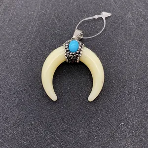Close-up of crescent bone pendant with turquoise bead and sparkling rhinestones