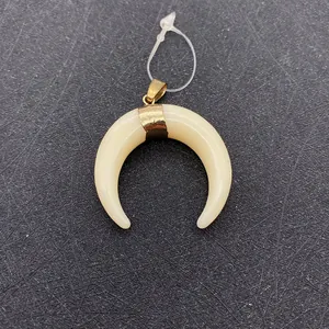 Detailed macro view of a creamy white resin crescent moon pendant with gold clasp