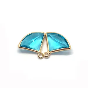 Macro detail of fan-shaped light blue faceted stone pendants with gold plated edges for DIY