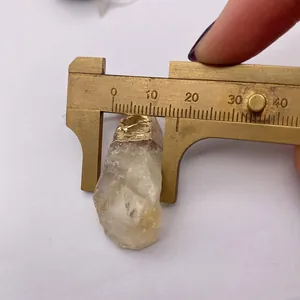 Detailed measurement of a natural crystal pendant with gold plating using a brass caliper