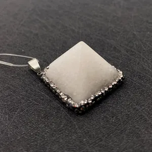 Detail view of a white pyramid gemstone pendant with rhinestone inlay and silver clasp