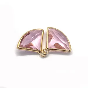 Macro view of pink crystal fan-shaped charms with faceted cut and gold metal edges