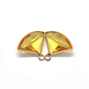 Macro detail of fan-shaped yellow crystal pendants with golden scalloped edges for DIY jewelry