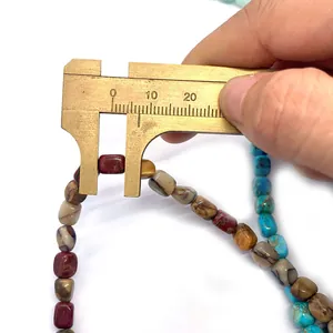 Macro shot showing 8mm irregular turquoise bead width measurement with a brass caliper