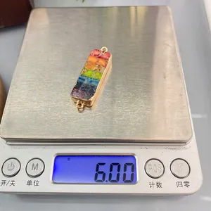 Macro shot of 6.00g colorful turquoise stone connector with gold rim on scale