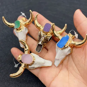 Bull skull pendants with colorful crystal stones held in hand for size comparison