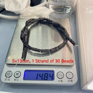 Close-up of 5x13mm natural black marble stone rectangular beads on a scale for DIY jewelry