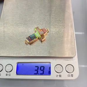 Detailed view of 3.91g cross stone pendant connector with gold plating on weighing scale