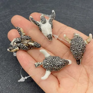 Close-up of four bull head pendants with sparkling rhinestones in a palm for size reference