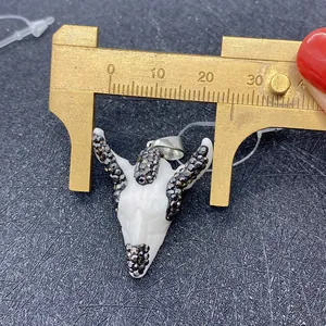 Macro shot of an acrylic bull skull pendant with inlaid rhinestones being measured
