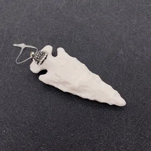 Détail d'un pendentif flèche en résine blanc laiteux avec calotte sertie de strass
