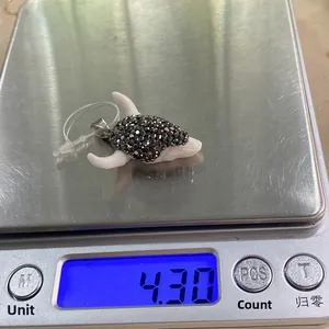 Colgante cabeza de toro con diamantes negros en báscula digital pesando 4,30 g