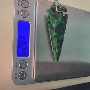 Mesure du poids d'un pendentif flèche en résine verte avec strass sur une balance digitale