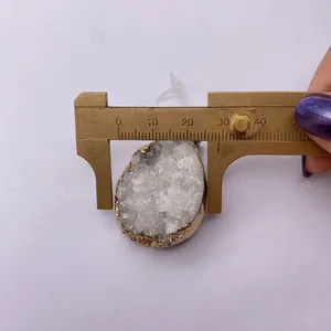 Detailed measurement of white crystal cluster pendant with gold plated edge and calipers