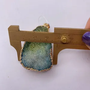 Macro view of natural crystal pendant showing 28mm width measurement with a brass caliper