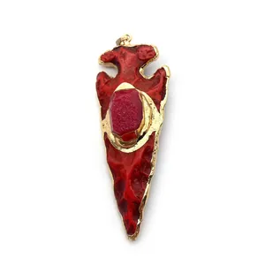 Détail d'un pendentif flèche en résine rouge avec texture et bordure en métal doré