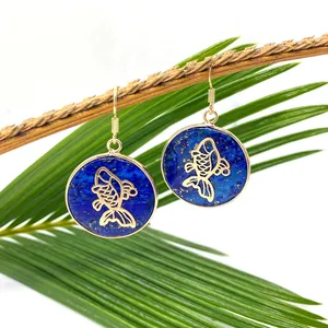 Lapis Lazuli round pendant earrings with gold fish motif and hook, set on a natural branch