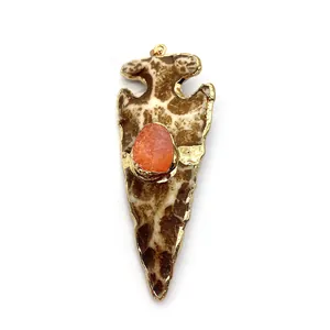 Détail d'un pendentif flèche en pierre naturelle avec centre orange et bordure dorée