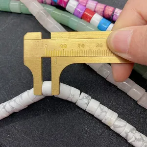 Macro shot showing 8mm cylinder white turquoise bead diameter with brass caliper measuring
