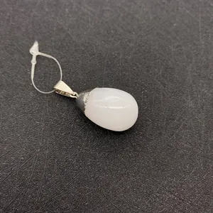 Macro detail of teardrop natural stone pendant with a textured silver-plated bail connector