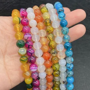 Dettaglio di perline di agata colorate da 8-10mm con motivi naturali tenute in mano