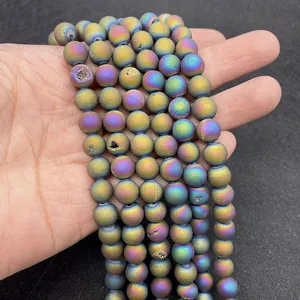 Detailed view of hand-held iridescent plated natural agate beads with crystal druzy texture