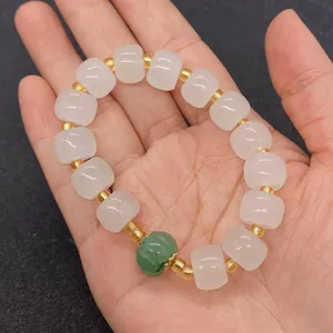Dettaglio del bracciale con perle di giada bianca e zucca verde con distanziatori oro