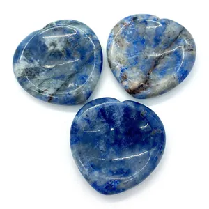 Gros plan de trois pendentifs en sodalite naturelle polie en forme de cœur sur fond blanc