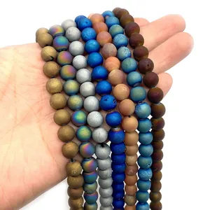 Hand holding assorted matte druzy agate round beads with electroplated metallic finish