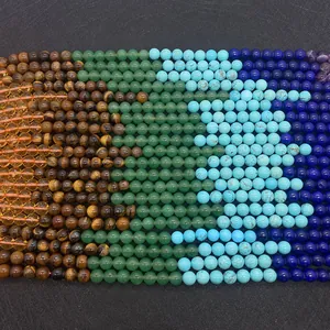 Macro shot of 6-8mm round natural stone beads like Tiger Eye and Lapis Lazuli on black texture