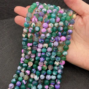 Detailopname van kleurrijke drakenader agaat kralen in de hand voor DIY-sieraden