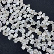 Detailed view of natural baroque pearls with silver-white luster on a dark background