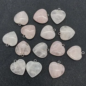 Flat lay of thirteen heart-shaped rose quartz stone pendants with silver bail connectors