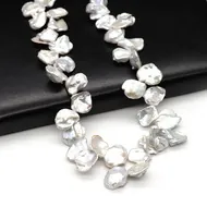 Macro detail of irregular baroque petal pearls with iridescent luster on black leather