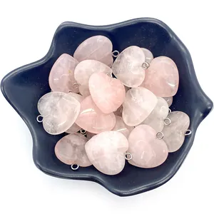 Polished natural pink rose quartz heart pendants with silver bails in a decorative tray
