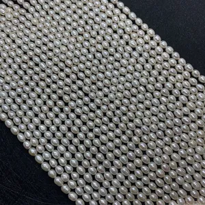 Perles d'eau douce blanches naturelles en forme de riz sur fond noir texturé