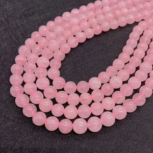 Macro shot of smooth 8-10mm natural rose quartz beads on a textured black display mat
