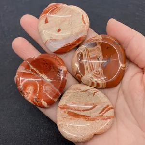 Gros plan de quatre pierres de jaspe rouge polies en forme de cœur tenues dans la main