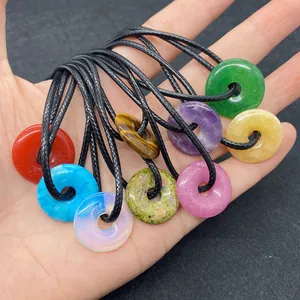 Gros plan de neuf pendentifs en pierre naturelle de 20 mm tenus dans une main