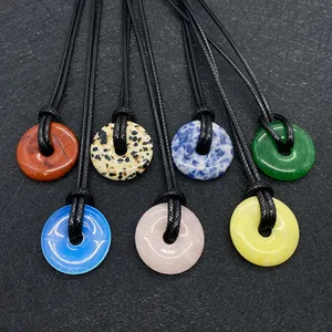 Detailed view of natural stone donut pendants in various colors with black woven cords