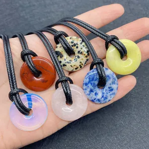 Detailed view of 20mm tiger eye stone ring pendants held in hand with cord necklaces
