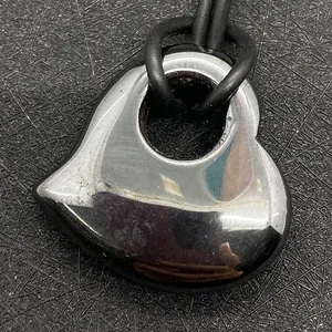 Close-up van hartvormige zilveren metalen hanger met reflecterend oppervlak aan zwart koord
