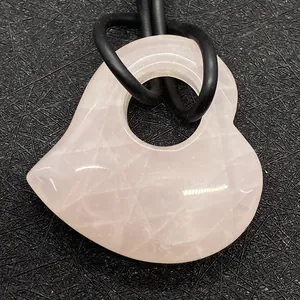 Macro-opname van een 30 mm rozenkwarts hartvormige hanger met zijgat op zwarte textuur