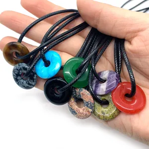 Pendentifs donuts en pierre naturelle avec cordon noir montrant diverses couleurs et textures