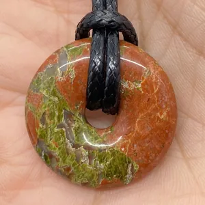 Macro detail of natural unakite donut pendant with green and pink stone textures