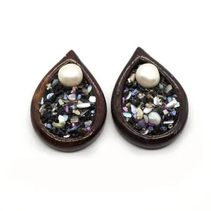 Détail de pendentifs en bois en forme de goutte avec perle blanche et pierres colorées