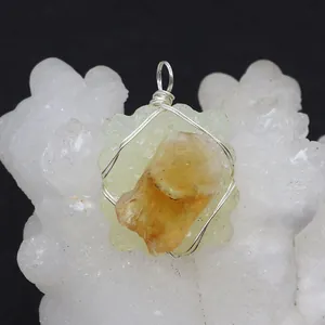 Macro detail of handmade wire wrapped yellow natural stone pendant on white mineral cluster