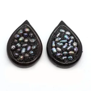 Détail macro de pendentifs goutte en résine avec perles irisées sur fond en résine noire
