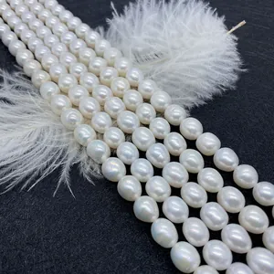 Ovale weiße Süßwasserperlen für DIY-Schmuck auf schwarzem Hintergrund mit Feder
