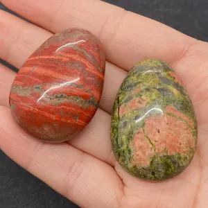 Pierres polies en Unakite et Jaspe rouge en forme de goutte tenues dans la main